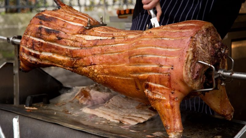 Buffet Catering Bloemfontein - whole pig roasting on a spit braai and being carved at an outdoor function Buffet Catering Bloemfontein - whole pig roasting on a spit braai and being carved at an outdoor function